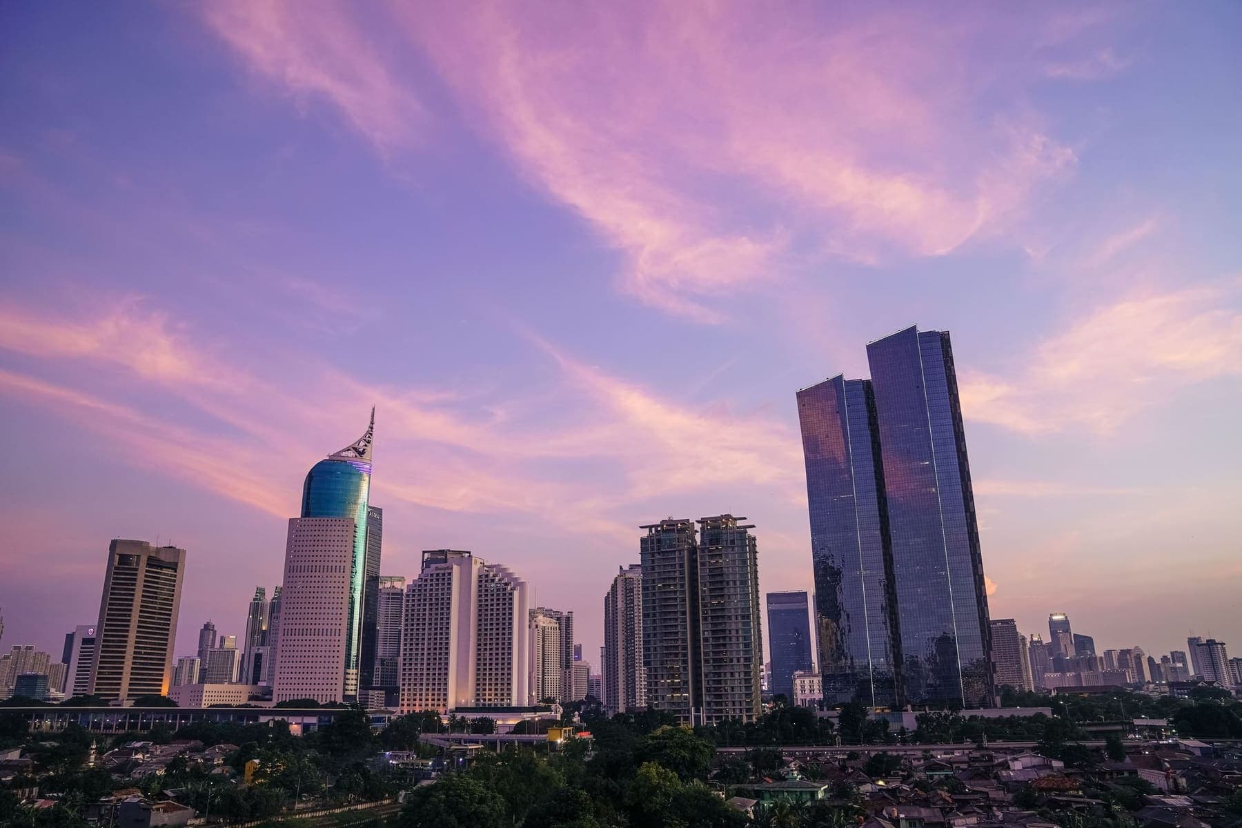 Cakrawala Jakarta saat senja, gedung perkantoran di bawah langit ungu