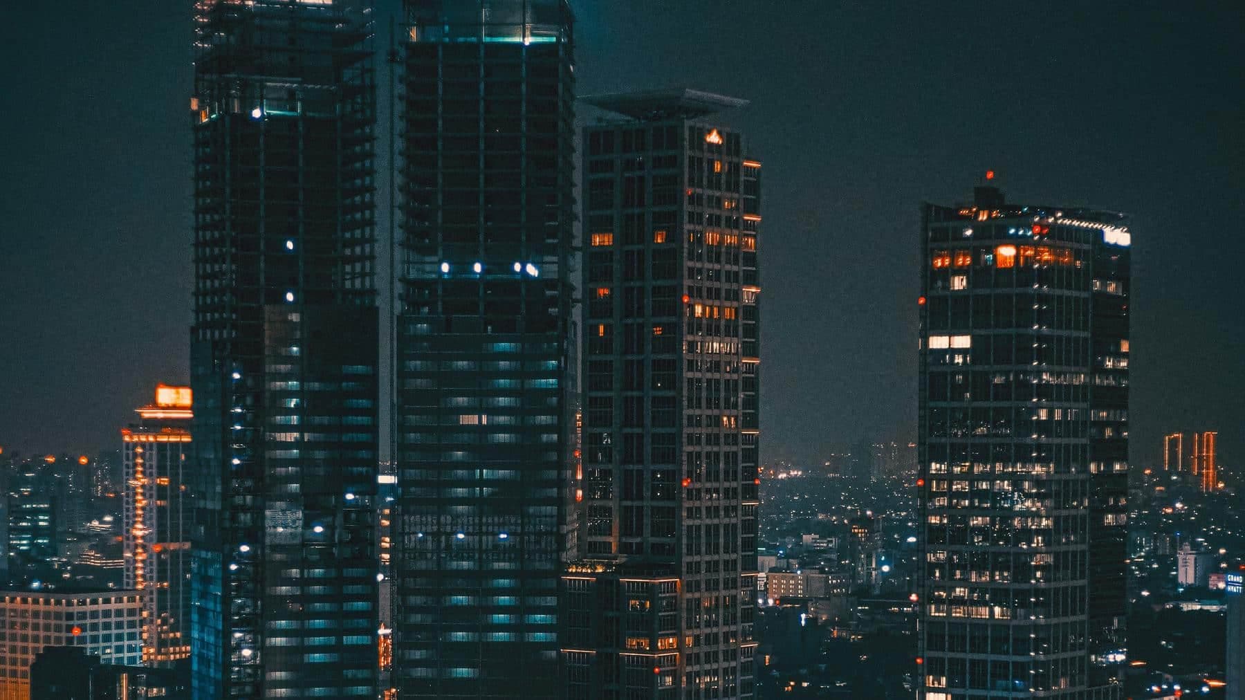Gedung-gedung tinggi Jakarta di malam hari dengan lampu jendela menyala